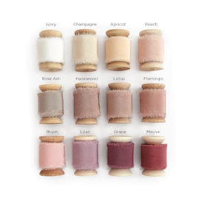 May include: Twelve spools of silk ribbon in various shades of pink, beige, and brown. The spools are arranged in three rows of four, with each spool labeled with a color name.