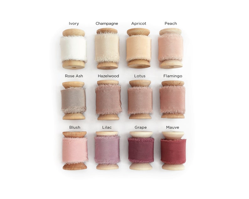 May include: Twelve spools of silk ribbon in various shades of pink, beige, and brown. The spools are arranged in three rows of four, with each spool labeled with a color name.
