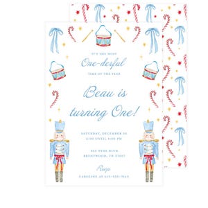 May include: A watercolor invitation with a festive design. The invitation features a blue drum, candy canes, bows, and a nutcracker soldier. Text reads "It's the Most One-derful Time of the Year" and "Beau is turning One!"
