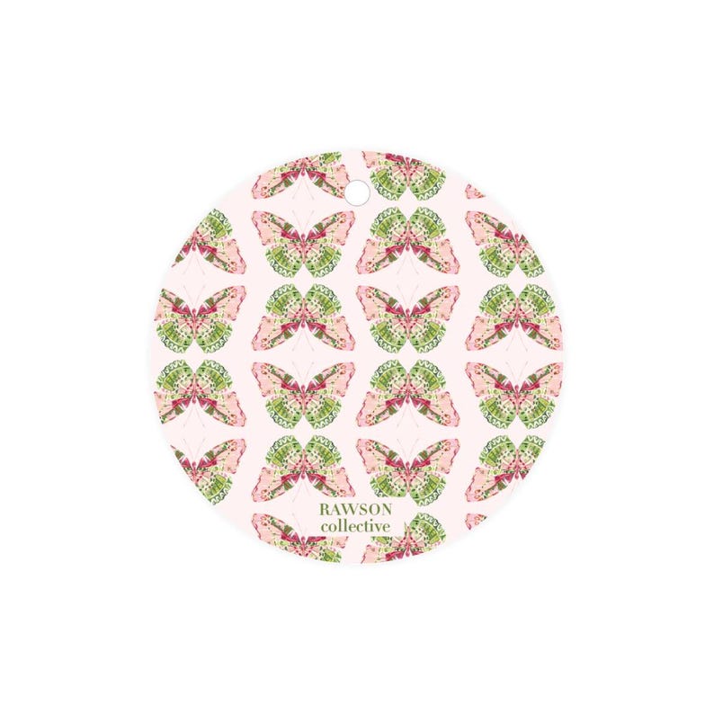 May include: Round ornament with a pink background and a repeating pattern of green and pink butterflies. The text "RAWSON collective" is printed in green at the bottom of the ornament.