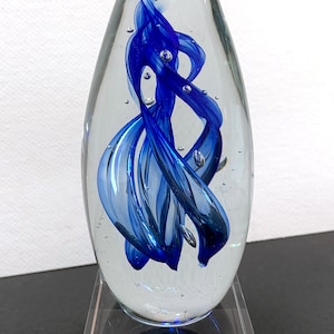 Puede incluir: Un pisapapeles de vidrio con un remolino azul en su interior, sentado sobre una base de vidrio transparente. La base está grabada con el texto "Best Boss Thanks Michael Rohan 2023".