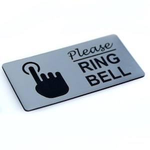 May include: A silver sign with black text and a black hand icon that says "Please Ring Bell".