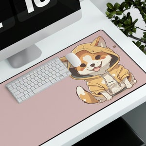 May include: A pink computer mouse pad with a cartoon illustration of a dog wearing a yellow hoodie. The dog is smiling and has a tongue sticking out. The mouse pad is on a white desk with a computer monitor and keyboard.