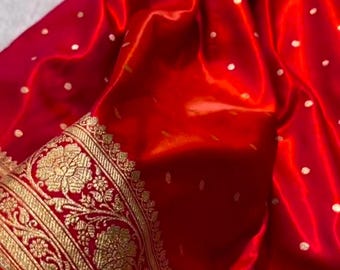 May include: Red silk saree with a gold border and white polka dots. The border features intricate floral designs.