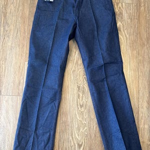 May include: A pair of dark blue denim jeans with a Wrangler tag attached to the waistband.