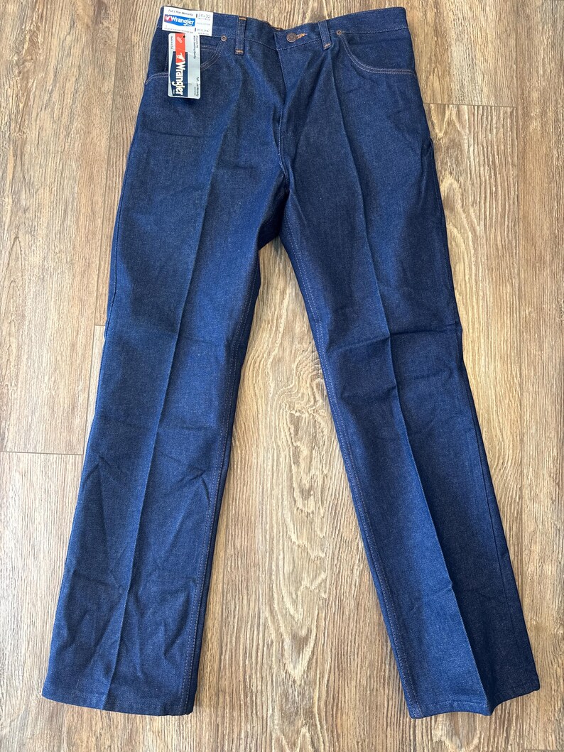 May include: A pair of dark blue denim jeans with a Wrangler tag attached to the waistband.