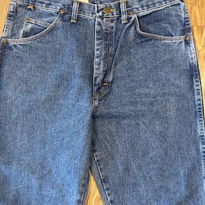 May include: A pair of blue denim jeans with a button fly and five pockets. The jeans have a faded look and are made of a soft, comfortable material.