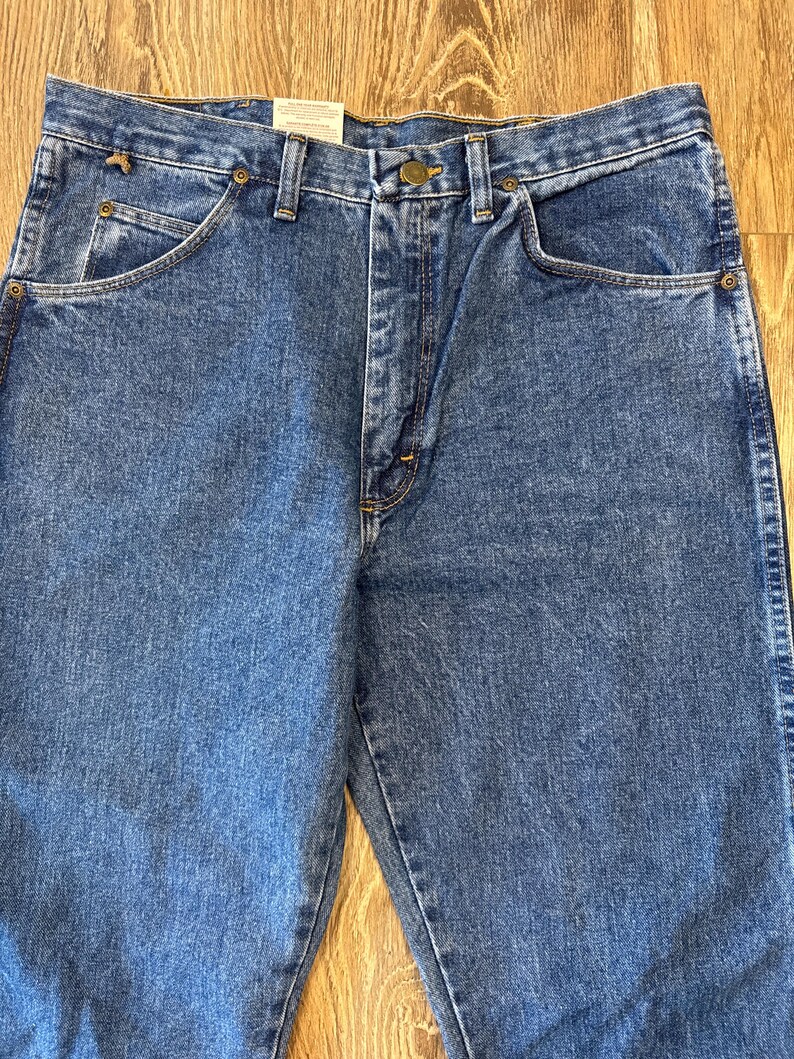 May include: A pair of blue denim jeans with a button fly and five pockets. The jeans have a faded look and are made of a soft, comfortable material.