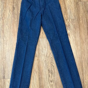 May include: A pair of dark blue denim jeans with a straight leg fit. The jeans have a button fly and belt loops.