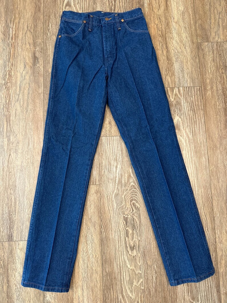 May include: A pair of dark blue denim jeans with a straight leg fit. The jeans have a button fly and belt loops.