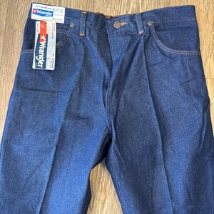 May include: A pair of blue denim jeans with a Wrangler tag attached. The tag says "Full Year Warranty" and "Wrangler" with the size "34 x 32".