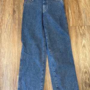 May include: Blue denim jeans with a classic five-pocket design. The jeans have a straight leg cut and a button and zipper closure. The denim has a medium wash and visible stitching.