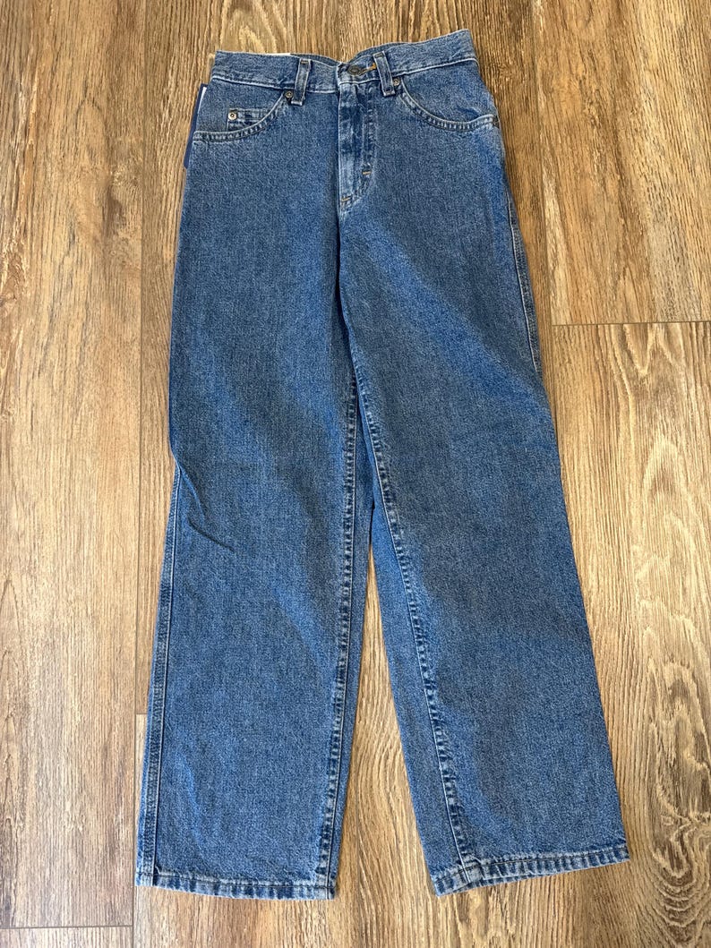 May include: Blue denim jeans with a classic five-pocket design. The jeans have a straight leg cut and a button and zipper closure. The denim has a medium wash and visible stitching.