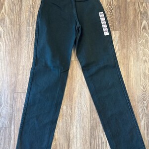 May include: Dark green straight leg jeans with a purple and white tag that says "Wrangler Rugged Wear" and "Made in the USA".
