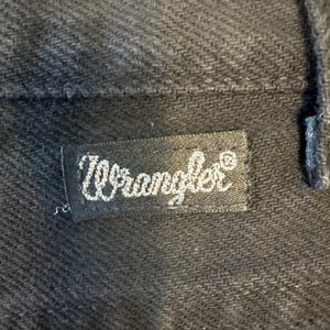 K&ouml;nnte beinhalten: Ein schwarzes Wrangler-Markenetikett mit wei&szlig;en N&auml;hten.