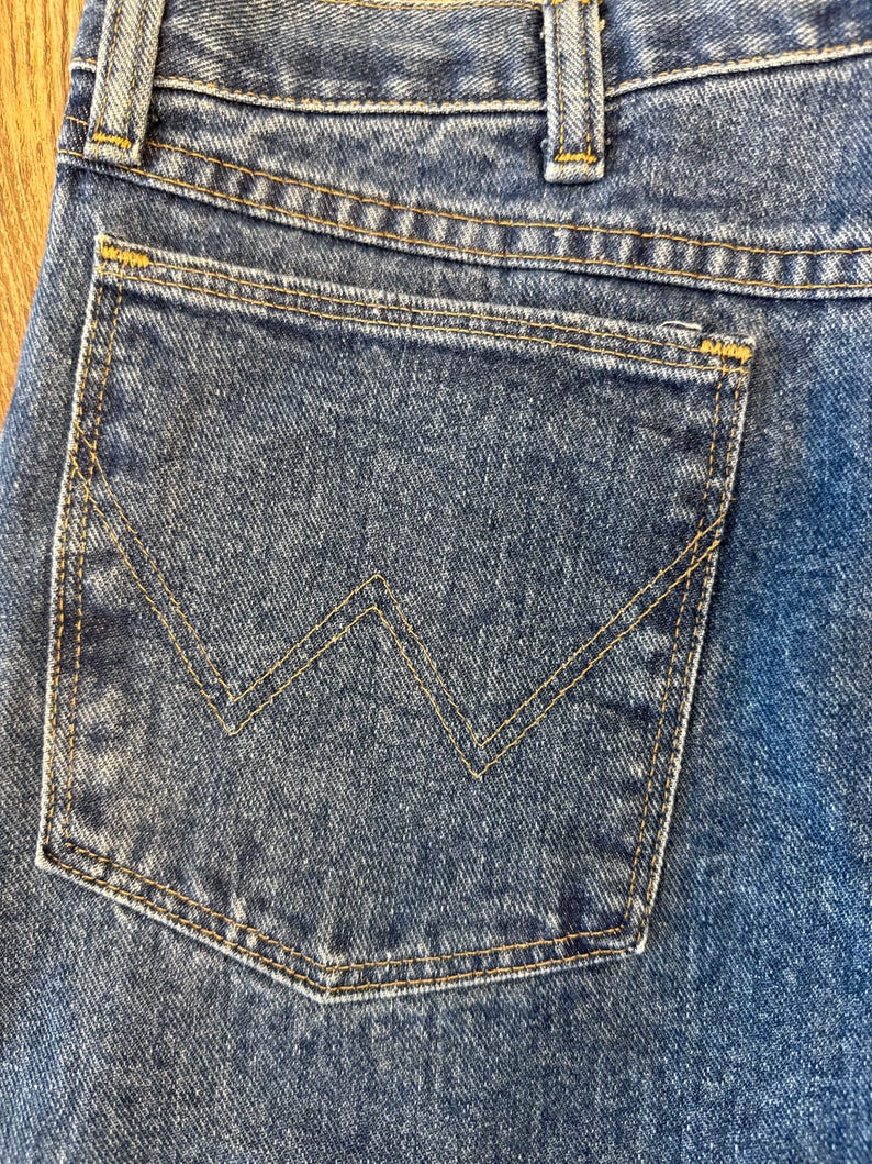 May include: A pair of blue denim jeans with a back pocket featuring a distinctive stitched 'W' design.
