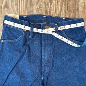 May include: A pair of blue denim jeans with a measuring tape wrapped around the waistband. The tape reads 24 to 37 inches.