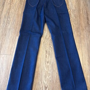 May include: A pair of dark blue denim jeans with a Wrangler tag. The jeans have a straight leg and a classic fit.