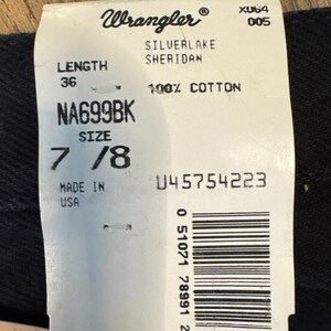 K&ouml;nnte beinhalten: Ein wei&szlig;es Etikett mit schwarzem Text, das auf eine Wrangler Silverlake Sheridan Jeans hinweist. Das Etikett zeigt die Gr&ouml;&szlig;e 7/8, die L&auml;nge 36, den Stil NA699BK und den Stoff 100% Baumwolle. Das Etikett enth&auml;lt auch einen Barcode und den Text "Hergestellt in den USA".