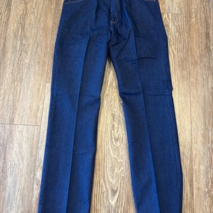 May include: A pair of dark blue denim jeans with a Wrangler brand tag. The jeans have a classic straight leg style.