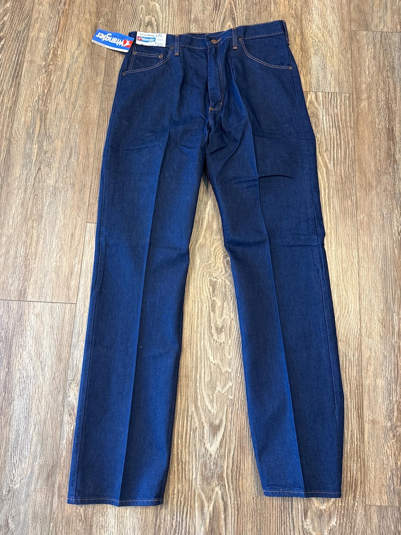 May include: A pair of dark blue denim jeans with a Wrangler brand tag. The jeans have a classic straight leg style.