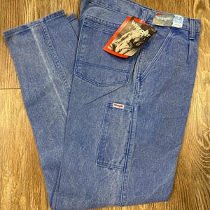 May include: Light blue Wrangler jeans with a straight leg and multiple pockets. The jeans have a faded wash and a red and white Wrangler tag. The waist size is 32 inches, and the inseam is 32 inches.