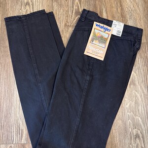K&ouml;nnte beinhalten: Schwarze gerade Jeans mit einem angebrachten Wrangler Silverlake-Etikett. Das Etikett zeigt eine Bergszene und den Text "Silverlake" in wei&szlig;er Schrift.