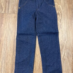 Puede incluir: Un par de pantalones vaqueros de mezclilla azul oscuro con corte recto. Los pantalones tienen cierre de bot&oacute;n y trabillas para cintur&oacute;n.