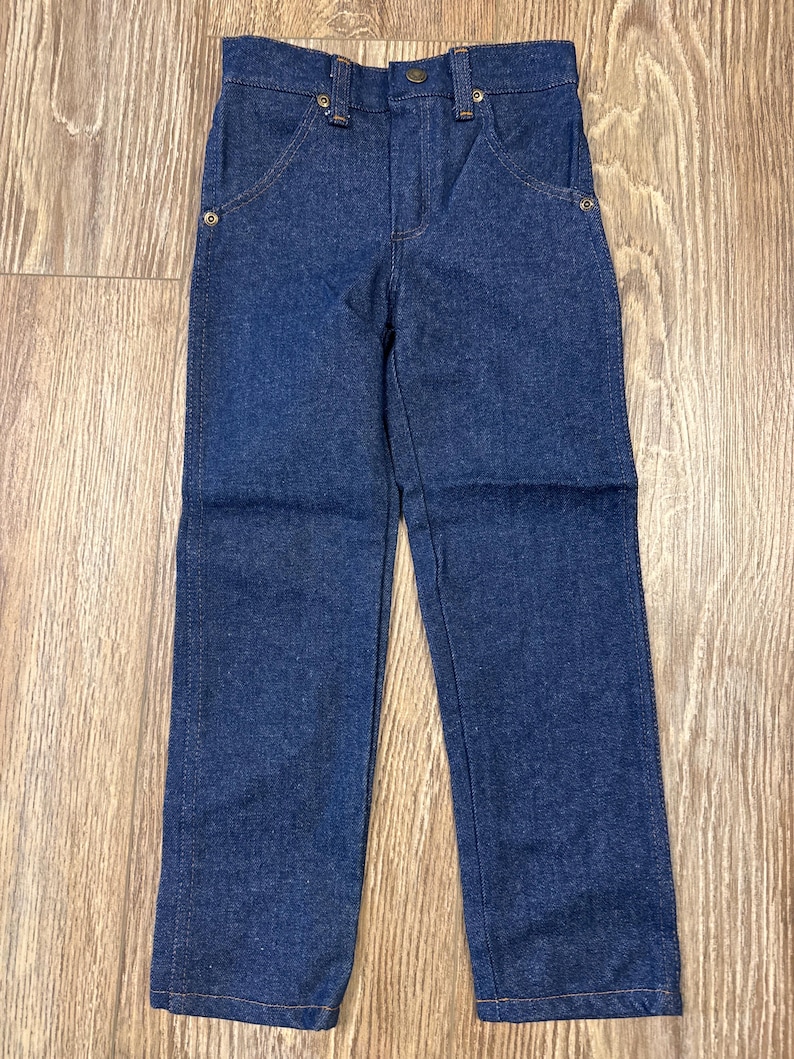 Puede incluir: Un par de pantalones vaqueros de mezclilla azul oscuro con corte recto. Los pantalones tienen cierre de bot&oacute;n y trabillas para cintur&oacute;n.