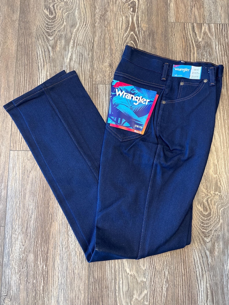 K&ouml;nnte beinhalten: Dunkelblaue Jeans aus Denim mit einem Wrangler-Etikett auf der Ges&auml;&szlig;tasche. Das Etikett zeigt das Wrangler-Logo und den Text "Stone Wash".