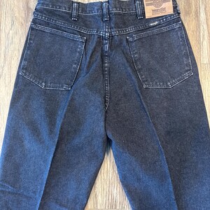 Puede incluir: Un par de pantalones vaqueros de color negro con una etiqueta de Wrangler de cuero marr&oacute;n en el bolsillo trasero.