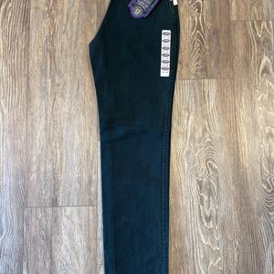May include: Dark green denim jeans with a Wrangler label and a size 12 tag. The jeans have a classic fit.