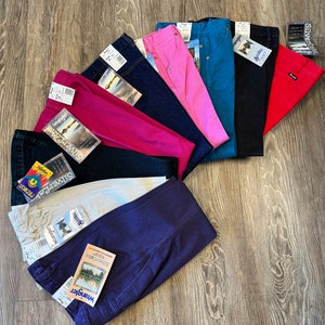 May include: A stack of ten pairs of blue, red, pink, white and beige jeans with the Wrangler Silver Jeans label.