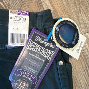 May include: Dark green Wrangler jeans with a purple and white tag that says "Bare Back" and "Classic Fit Long Rise". The tag also says "No Back Pockets" and "Tapered Leg Fits Over Boots".