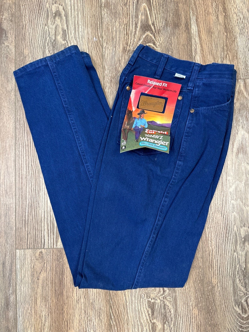 May include: A pair of dark blue denim jeans with a relaxed fit. The jeans have a label on the back pocket that says "Relaxed Fit" and "Wrangler".