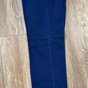 May include: Dark blue denim jeans with a relaxed fit. The jeans have a label that says "Relaxed" and "Wrangler" on it.