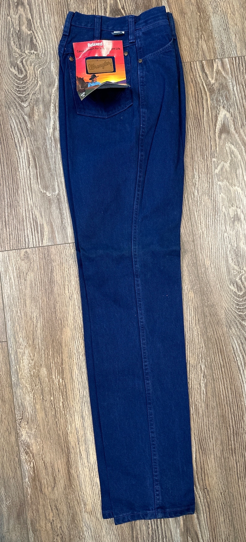 May include: Dark blue denim jeans with a relaxed fit. The jeans have a label that says "Relaxed" and "Wrangler" on it.