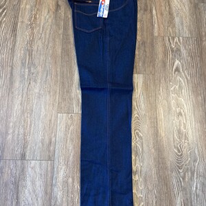 Peut inclure: Un jean en denim bleu fonc&eacute; avec une &eacute;tiquette Wrangler. Le jean a une coupe droite et un style classique &agrave; cinq poches.