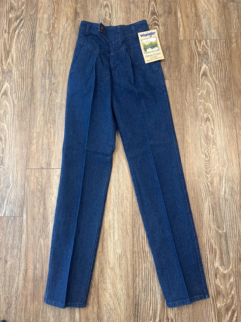 Puede incluir: Vaqueros Wrangler Silver Edition de mezclilla azul con cintura alta y pliegues. Los vaqueros tienen cierre de bot&oacute;n y una etiqueta adjunta. Los vaqueros est&aacute;n hechos de un material de mezclilla duradero.