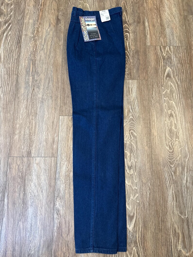 Puede incluir: Pantalones vaqueros azul oscuro con dise&ntilde;o de pernera recta. Los pantalones tienen un estilo cl&aacute;sico de cinco bolsillos y cremallera. Una etiqueta con la marca "Wrangler SilverCake" est&aacute; adjunta.