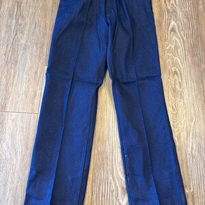 Peut inclure: Un jean en denim bleu fonc&eacute; avec une &eacute;tiquette Wrangler. Le jean a une jambe droite et une coupe classique &agrave; cinq poches.