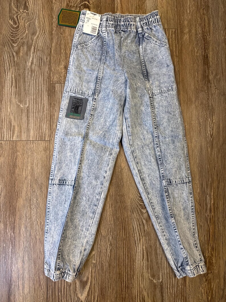 K&ouml;nnte beinhalten: Jeanshose mit S&auml;urewaschung, elastischem Bund und einem Aufn&auml;her am linken Bein. Die Hose hat einen hellblauen und wei&szlig;en Marmoreffekt. Die Hose hat Taschen und ist an den Kn&ouml;cheln ger&uuml;scht. Ein Etikett ist am Bund befestigt.