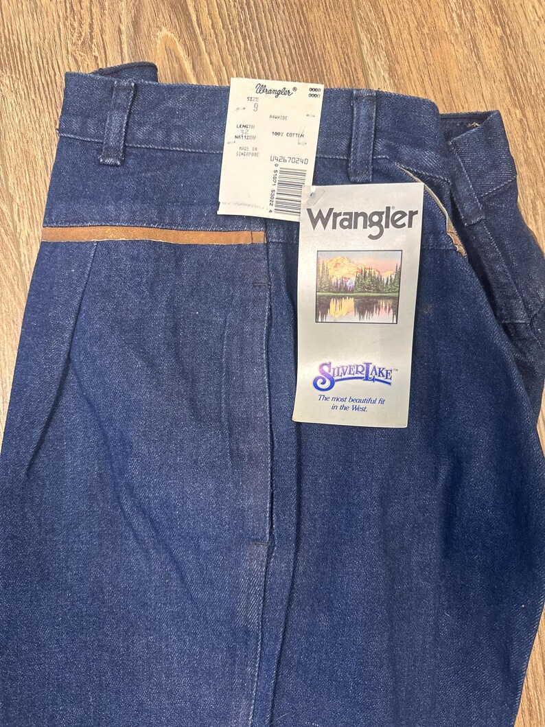 Puede incluir: Un par de pantalones vaqueros azules con una cintura de cuero marr&oacute;n. Los vaqueros tienen una etiqueta que dice "Wrangler Silverlake" y "The most beautiful fit in the West".