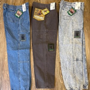 K&ouml;nnte beinhalten: Drei Wrangler Rugged Wear Cargo-Hosen in blauem Denim, Braun und Acid-Wash-Denim. Jede Hose hat einen Aufn&auml;her am Bein und ein Etikett. Die Hosen haben einen elastischen Bund und B&uuml;ndchen.