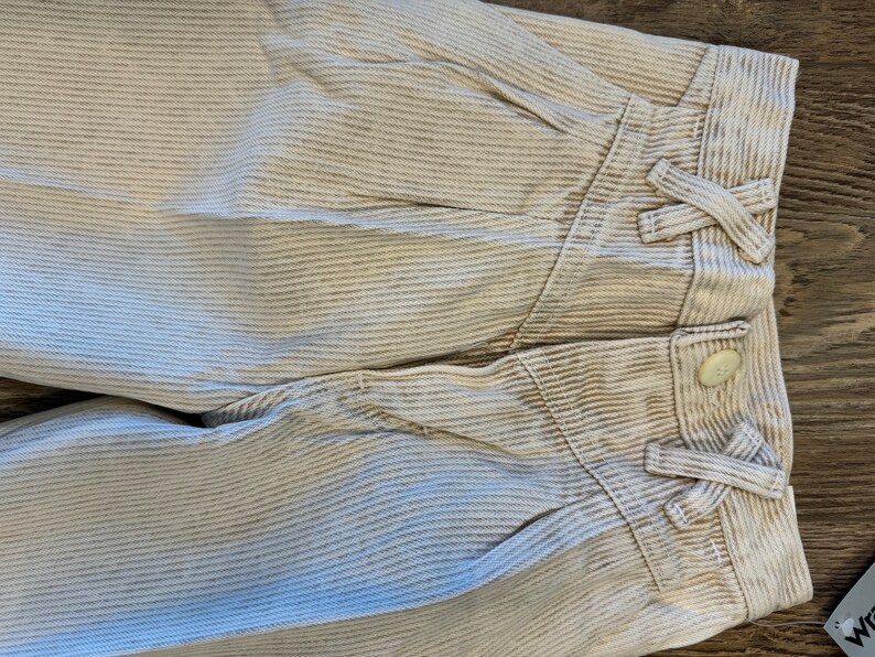 May include: A pair of white corduroy trousers with a striped pattern. The trousers have a button fastening and a tie at the waist.