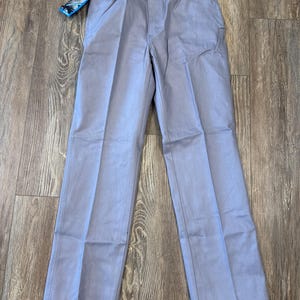 May include: Light blue Wrangler pants with a straight leg design. The pants have a classic five-pocket style and a tag attached to the waistband. The pants are made of a durable fabric and are suitable for everyday wear.