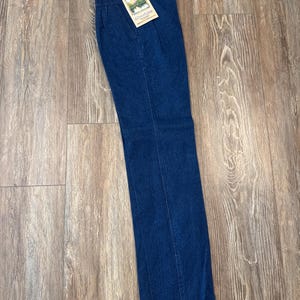 Puede incluir: Vaqueros Wrangler de mezclilla azul oscuro con cintura alta y pernera recta. Los vaqueros tienen una etiqueta que dice "Wrangler" y "Silverlake Vintage". Los vaqueros son nuevos con etiquetas.