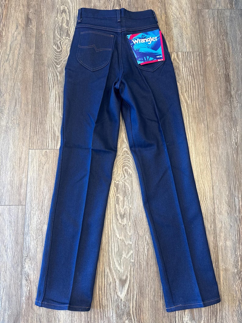 K&ouml;nnte beinhalten: Eine dunkelblaue Jeanshose mit einem Wrangler-Etikett auf der Ges&auml;&szlig;tasche.