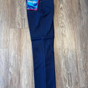 K&ouml;nnte beinhalten: Dunkelblaue Jeans aus Denim mit einem Wrangler-Etikett auf der Ges&auml;&szlig;tasche.