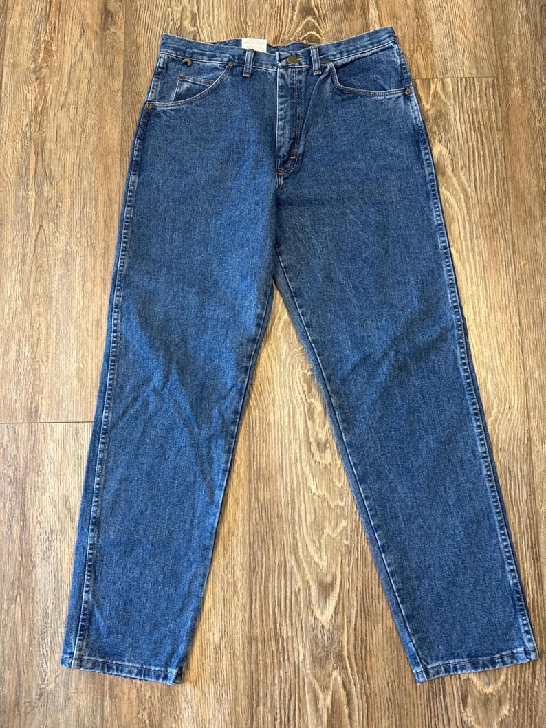 May include: A pair of blue denim jeans with a straight leg fit. The jeans have a button fly and belt loops.
